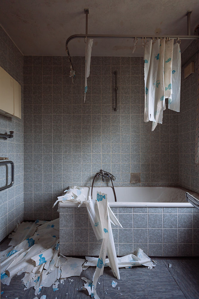 verlassenes Badezimmer mit Badewanne und besch&auml;digtem Duschvorhang